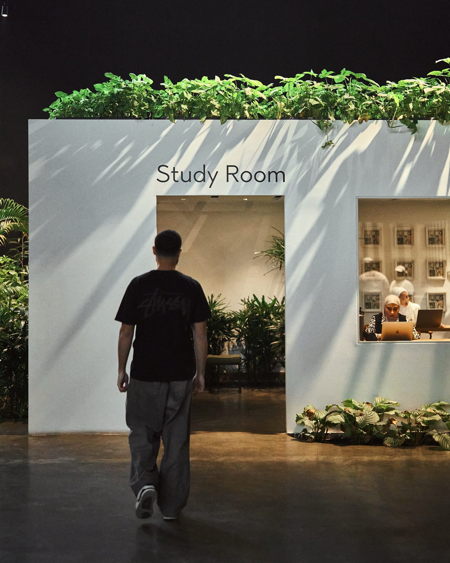 A guest walking up to the Study Room doorway, with two guests at their laptops behind its window